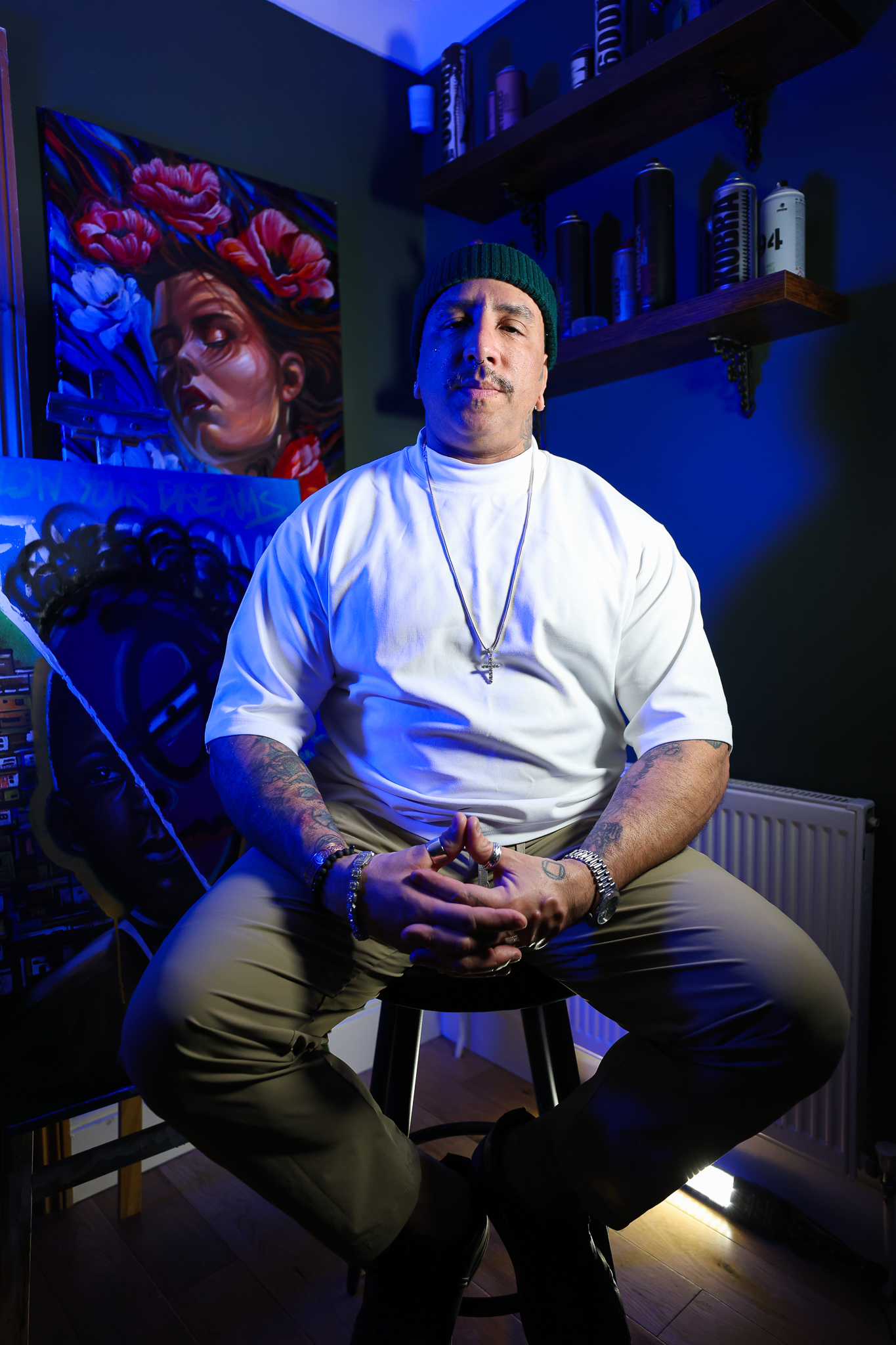 André Fila in blue light beside his paintings